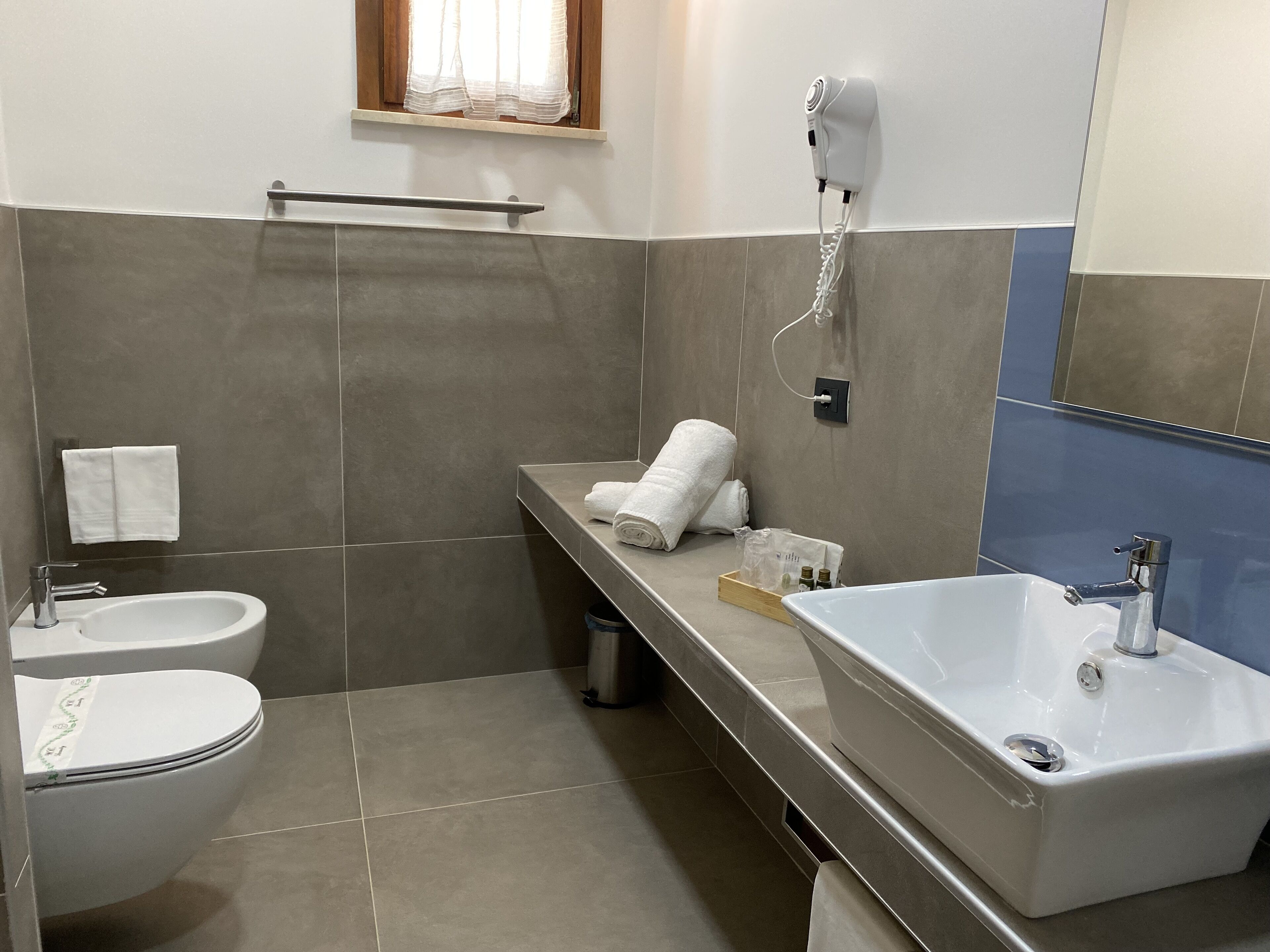 Ein modernes Badezimmer mit Toilette, Bidet und einem großen Waschbecken.