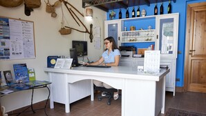 Un mostrador de recepción con una computadora, un tablón de anuncios informativo y una exhibición de vinos.