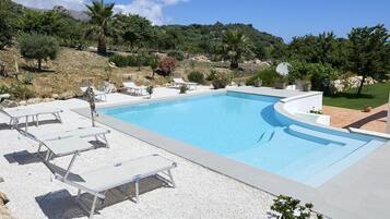 En säsongsöppen utomhuspool, parasoller och solstolar