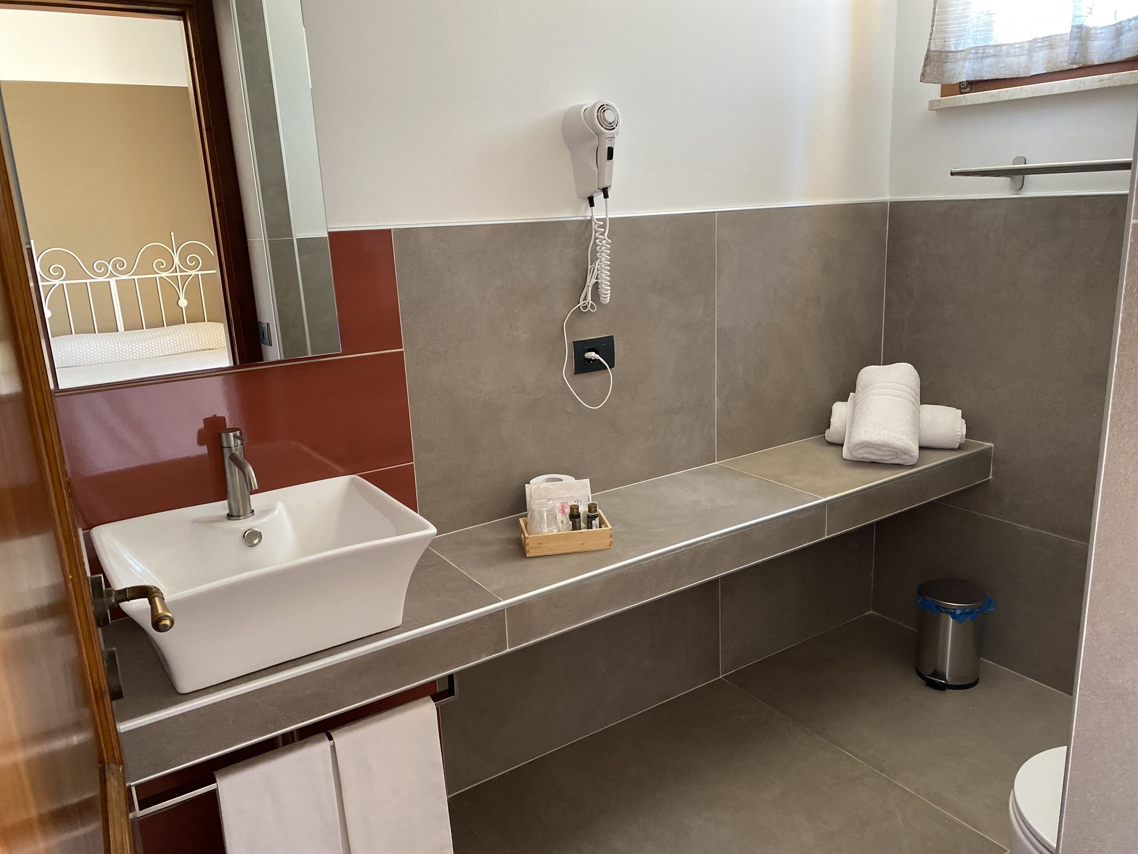 A modern bathroom with a white sink, a hairdryer, and a towel rack.