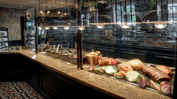 A buffet counter with various meats, vegetables, and bread. - The Bold Hotel, BW Signature Collection (Southport)
