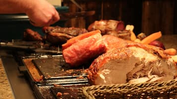 Un pavo asado en una parrilla, alguien lo está cortando.