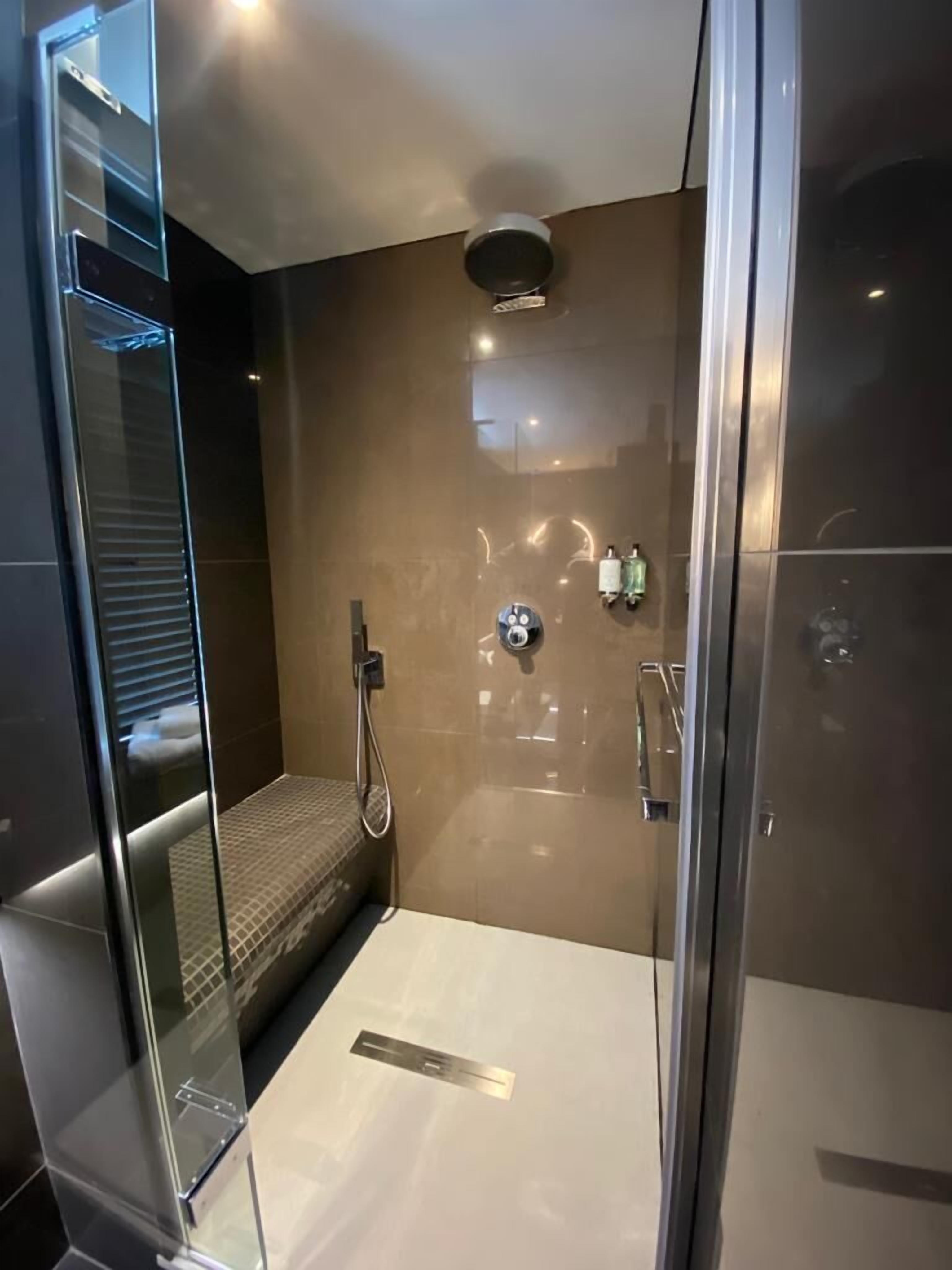 Ein modernes Badezimmer mit Duschkabine aus Glas, Handbrause und Wandarmatur.