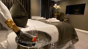 A modern hotel room with a bed, a bucket of champagne, and a vase with flowers. - The Bold Hotel, BW Signature Collection (Southport)