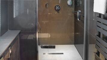 Un baño moderno con ducha envuelta en vidrio, una bañera independiente y un inodoro.
