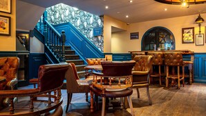 A hotel lobby with a grand staircase, leather seating, and a marble wall. - The Bold Hotel, BW Signature Collection (Southport)