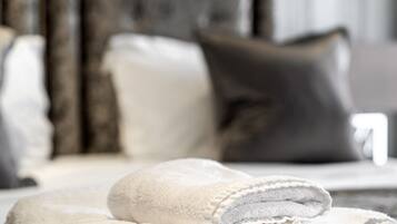 A neatly made bed with folded white towels and a dark headboard.