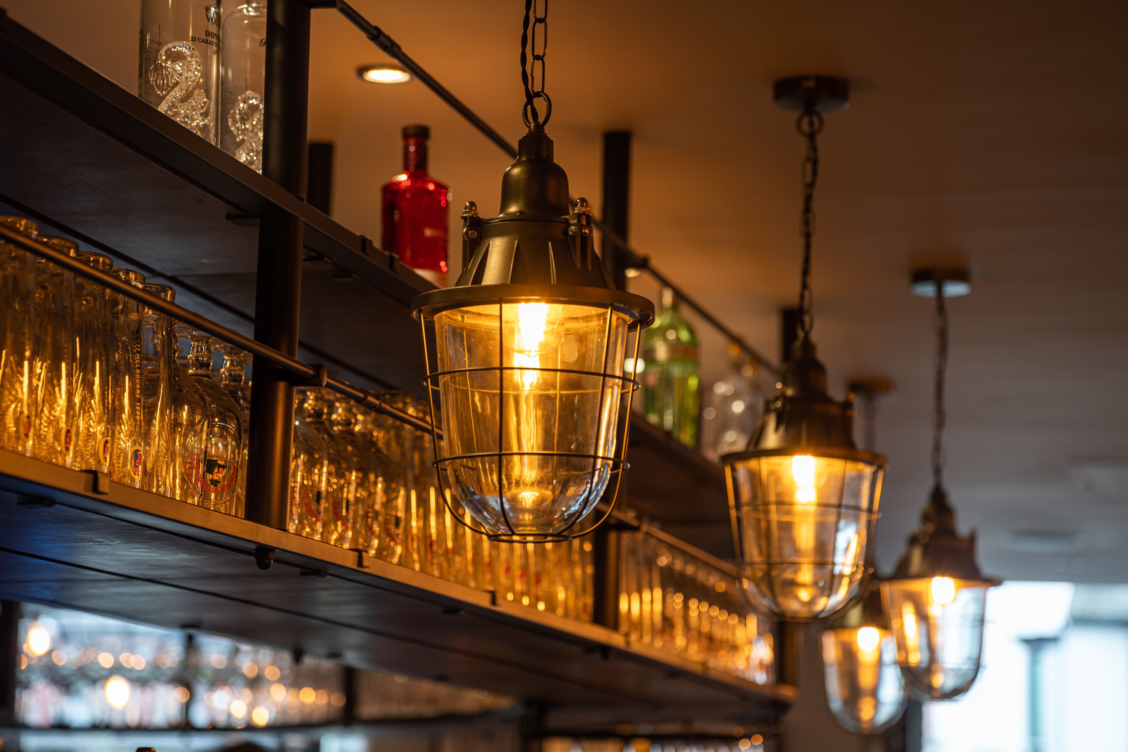 A bar with hanging lights and shelves of bottles.