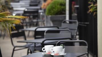 Une rangée de tables et de chaises installées à l’extérieur, avec une enseigne indiquant « The Bold » en arrière-plan.