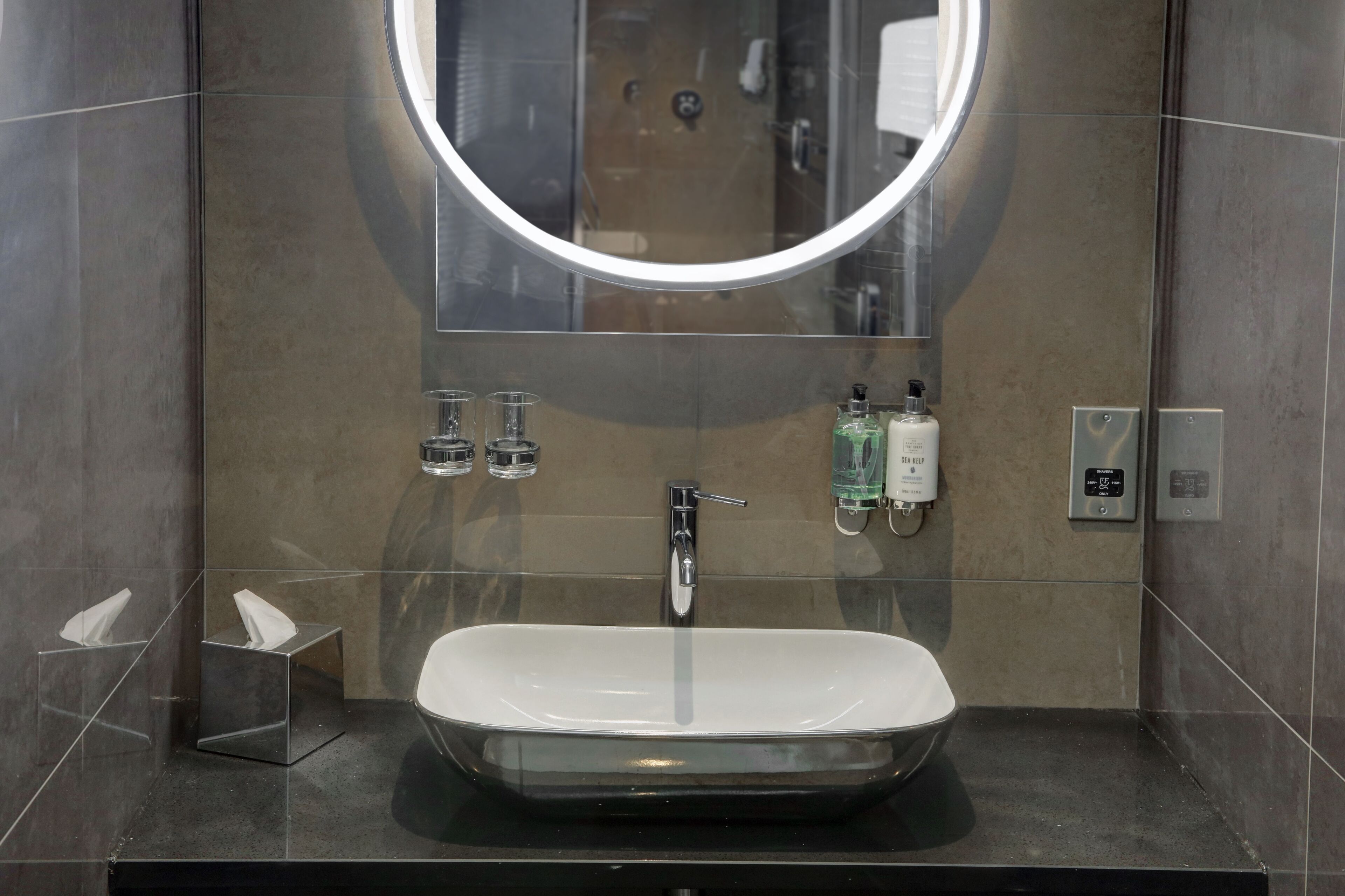 A modern bathroom with a large mirror, a rectangular sink, and a towel rack.