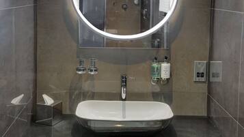 A modern bathroom with a large mirror, a rectangular sink, and a towel rack.