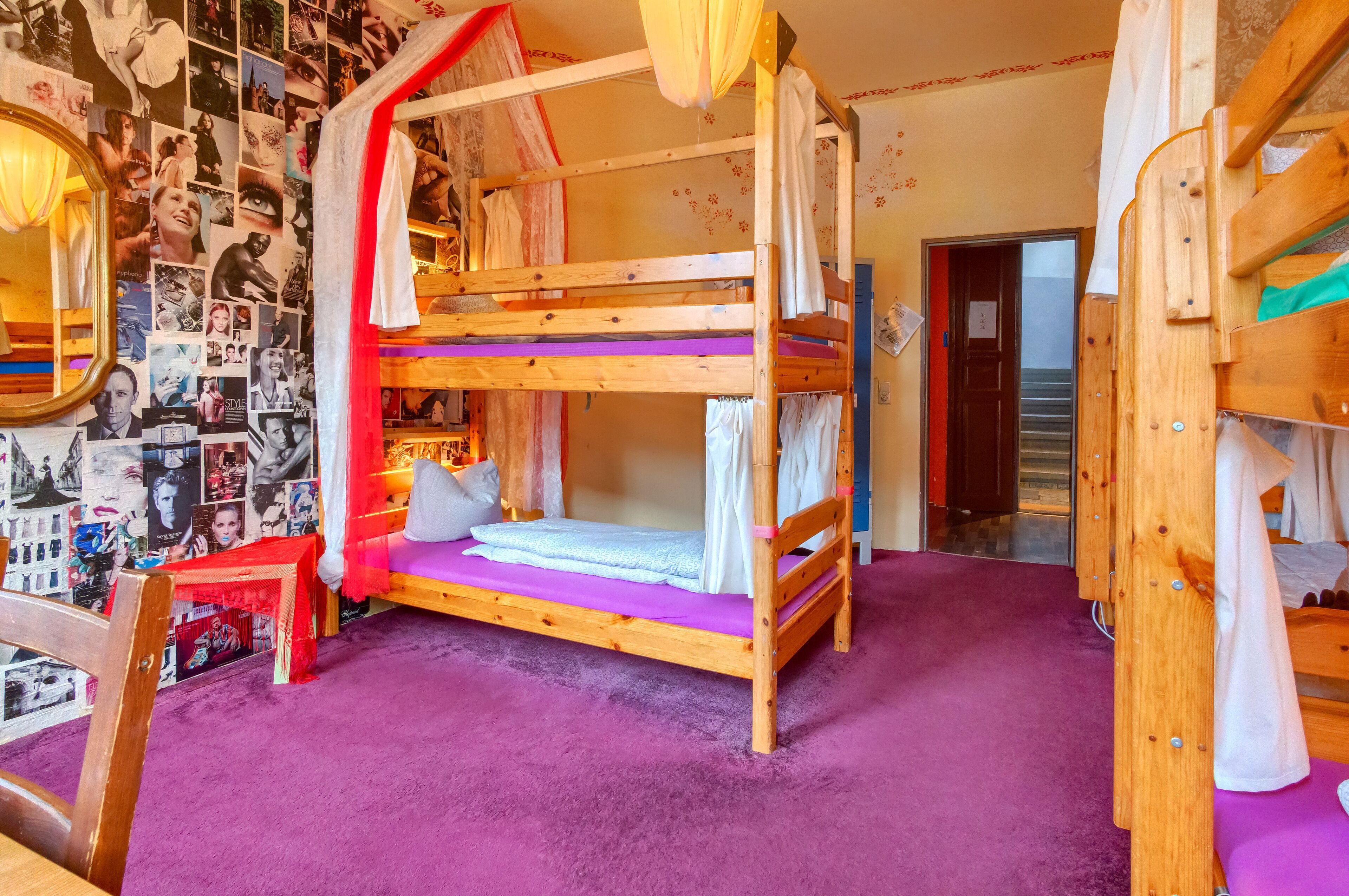 Habitación con literas, alfombra morada, un espejo y una pared llena de fotos.