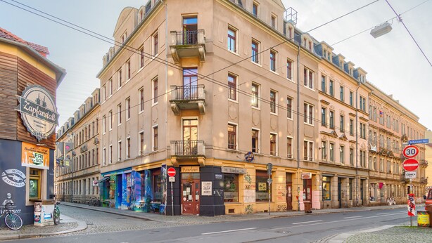 Un edificio en esquina con varios locales comerciales, incluyendo un albergue y un restaurante.