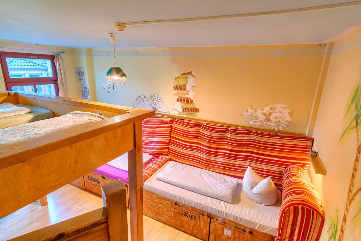 A cozy room with a bunk bed, a cushioned bench, and a wall-mounted bookshelf.