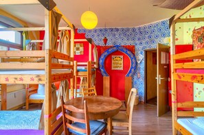 A room with bunk beds, a round wooden table, and chairs. - Lollis Homestay - Hostel (Dresden)