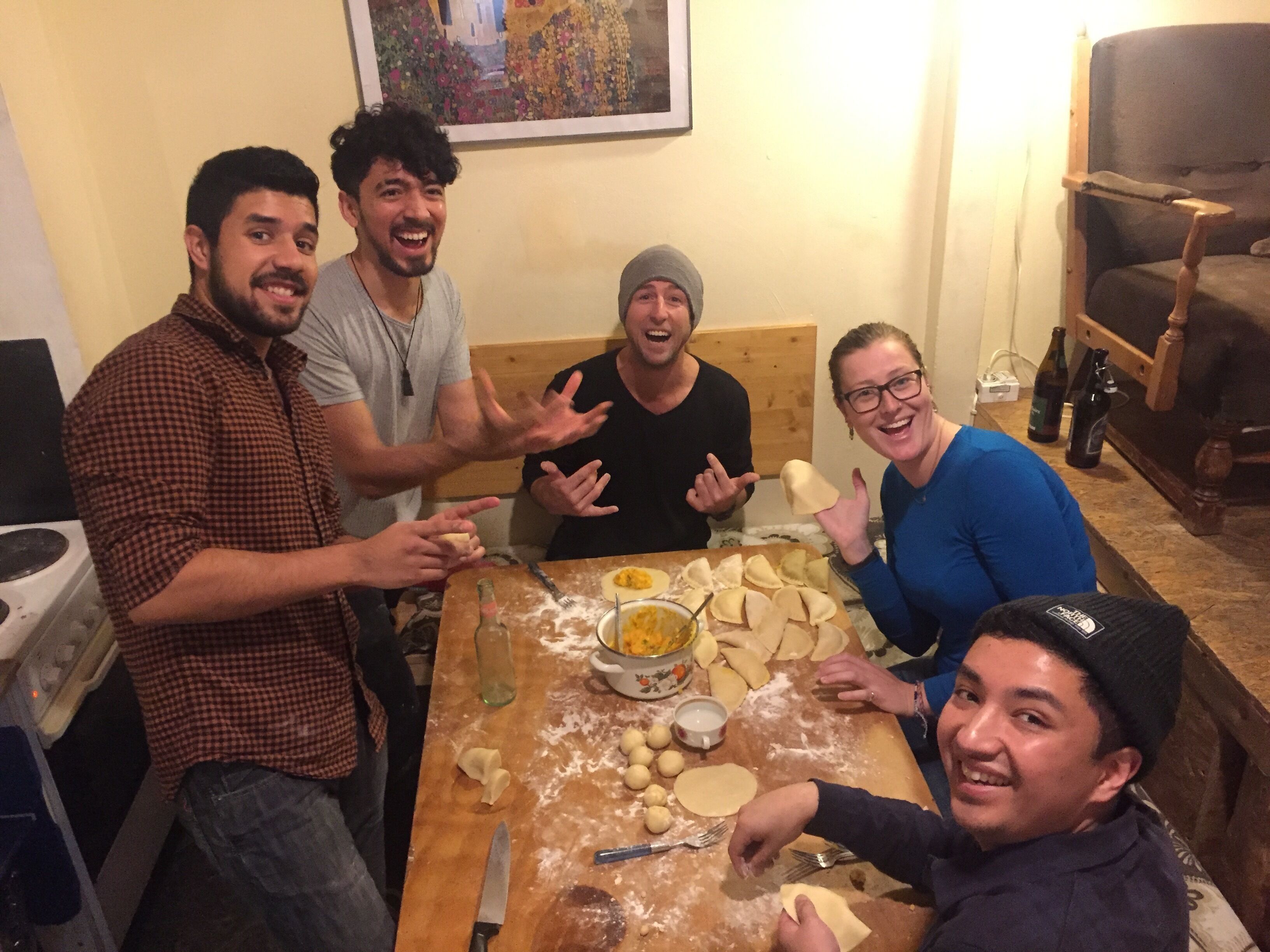 A group of people around a table with dough and utensils, suggesting a cooking activity.