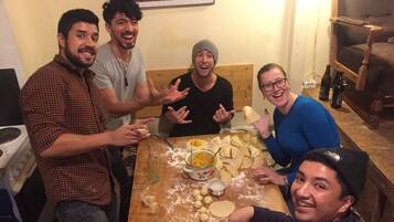 A group of people around a table with dough and utensils, suggesting a cooking activity.