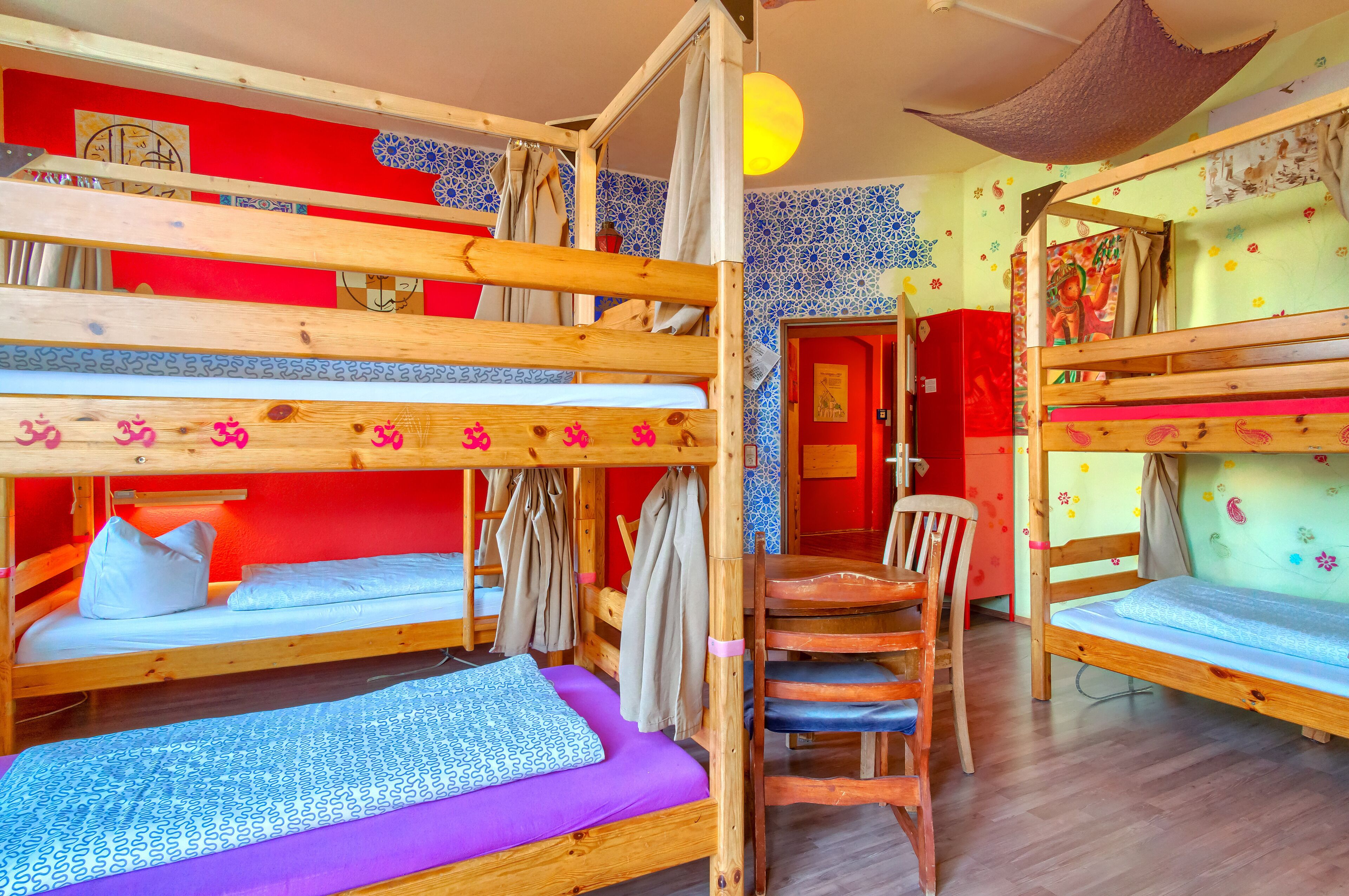 A room with bunk beds, a wooden chair, and a red wall with decorative elements.