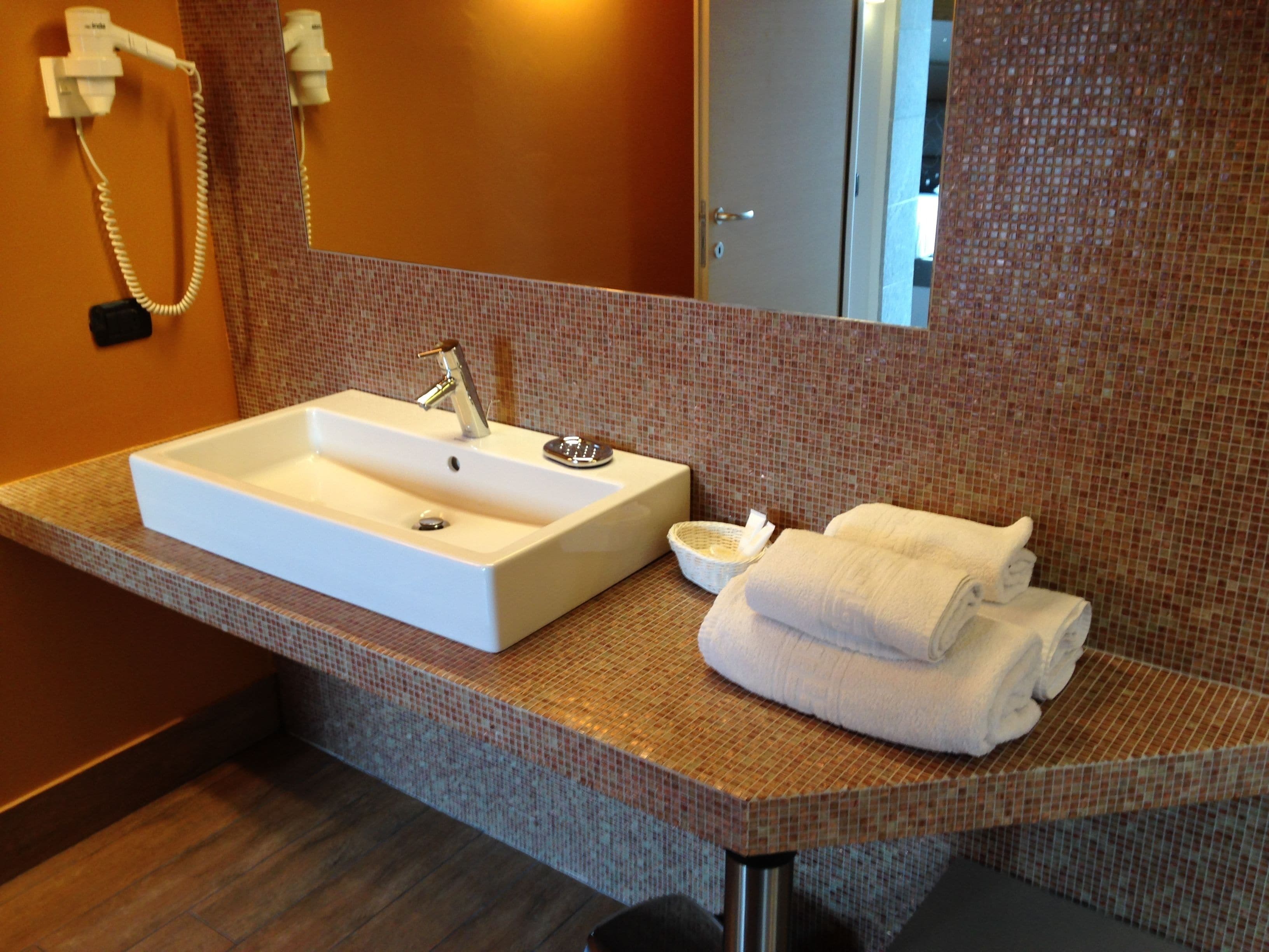 A bathroom with a white sink, a mirror, and a towel rack.