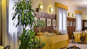 A dining area with yellow tablecloths, chandeliers, and framed artwork on the walls. - Don Abbondio (Lecco)