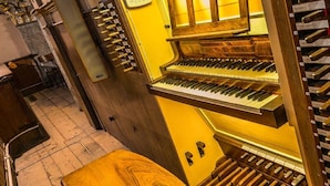 A grand piano in a room with a tiled floor and wooden walls. - Don Abbondio (Lecco)