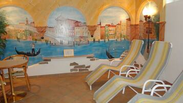 A room with a mural of a canal scene, lounge chairs, a table, and a tiled floor.