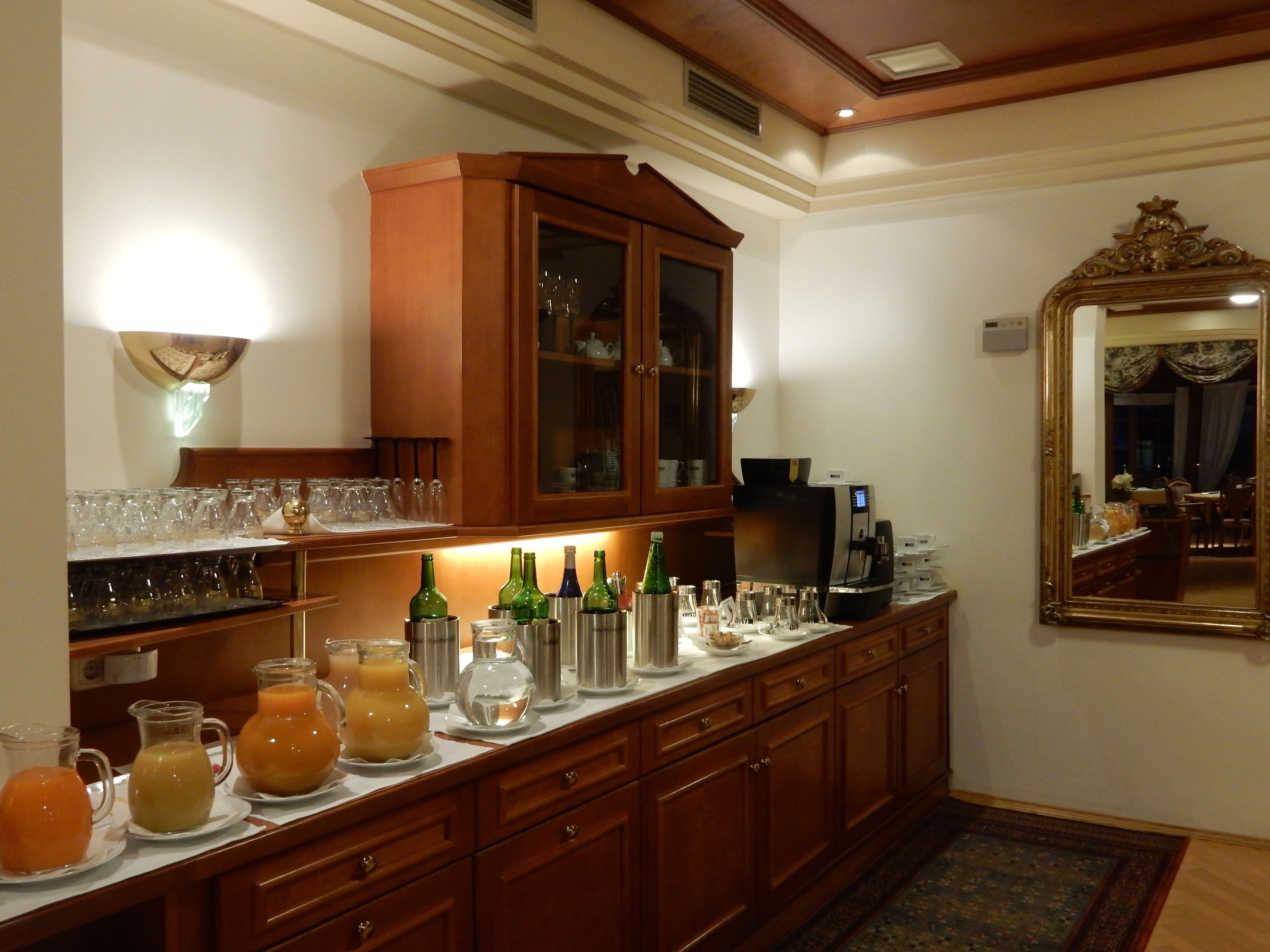 Una zona de bar con un mueble de madera, una cafetera y diversos vasos y botellas.