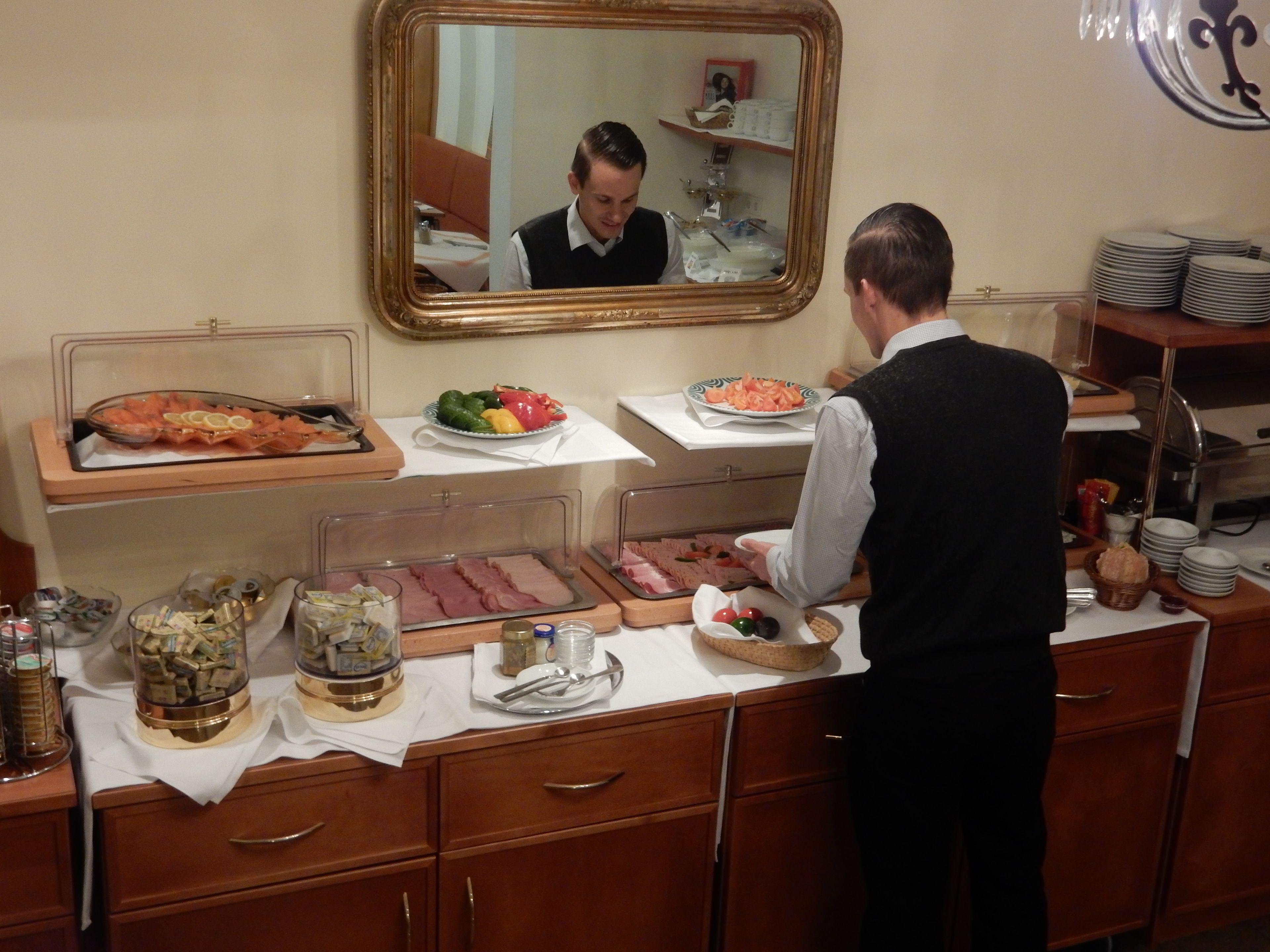 Una mesa de buffet con diferentes alimentos y un espejo que refleja la escena.