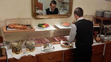 Una mesa de buffet con diferentes alimentos y un espejo que refleja la escena.
