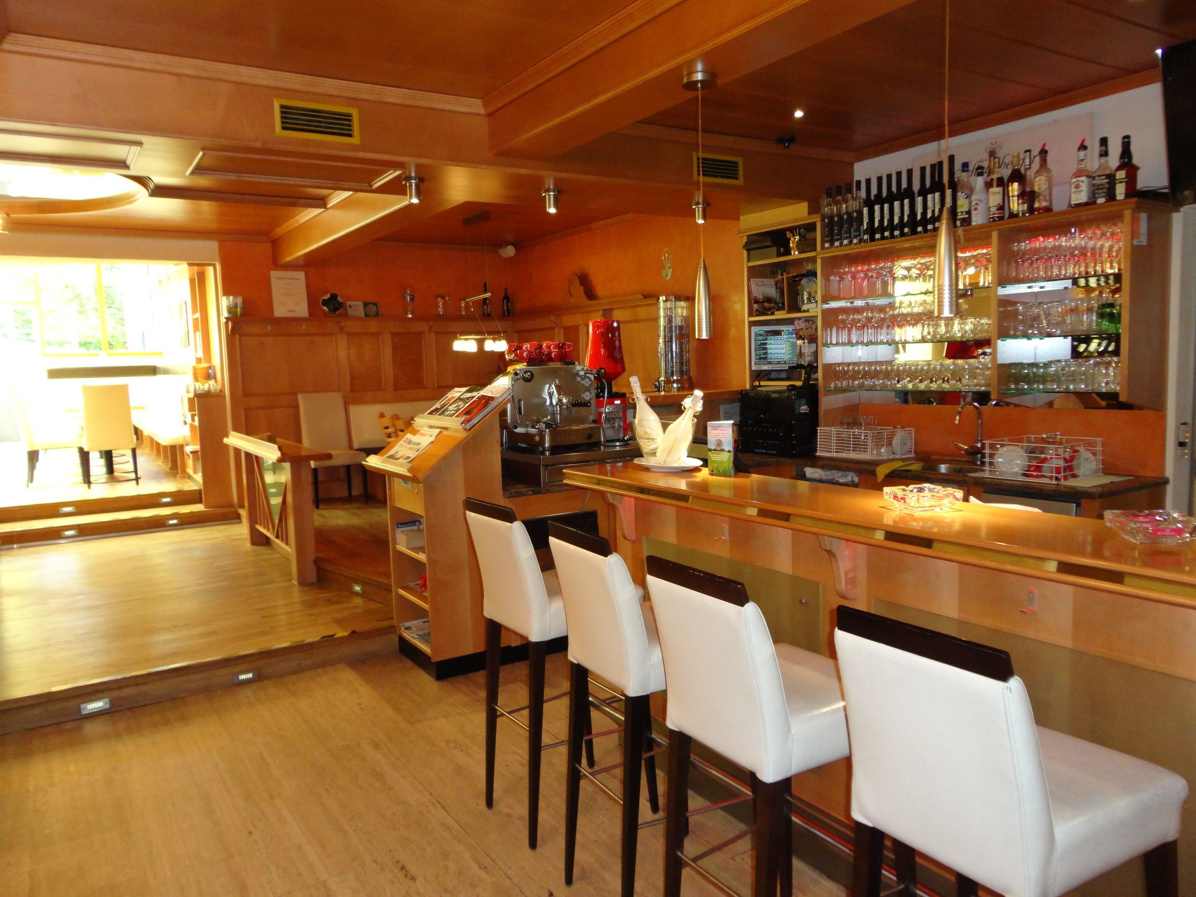 Un espace bar comprenant un comptoir, des tabourets de bar, un réfrigérateur à vin et un présentoir à bouteilles.