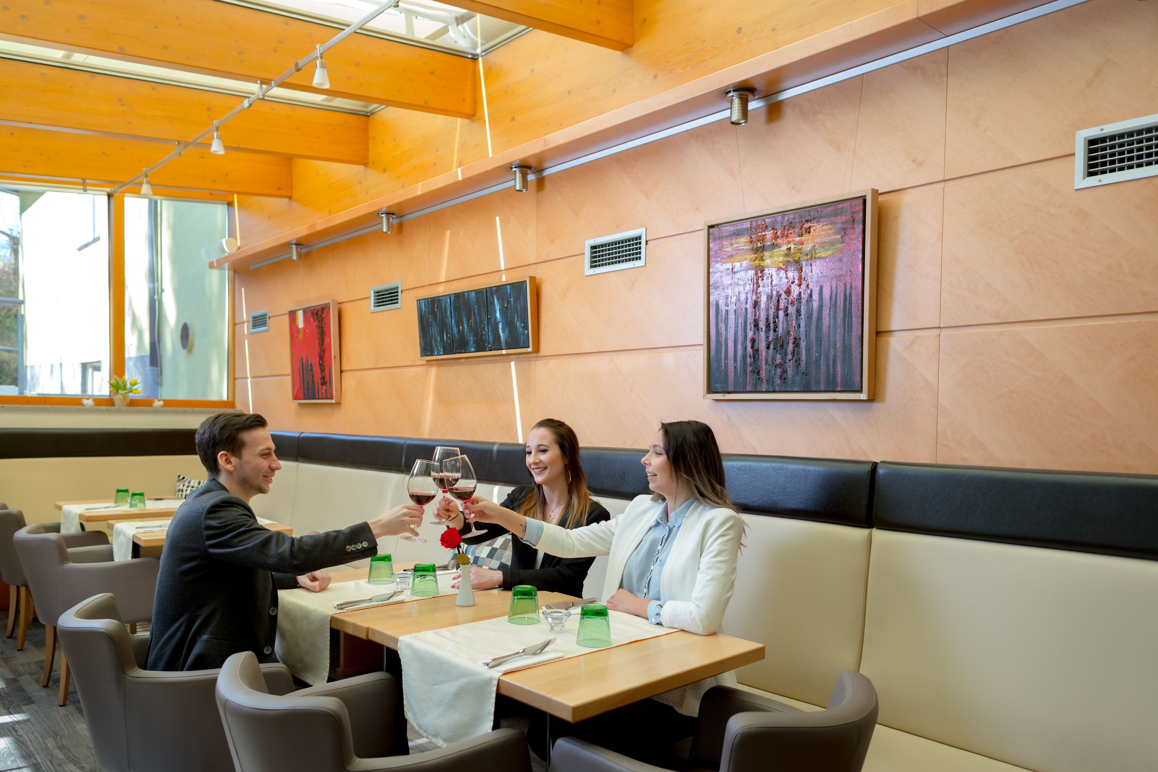 A restaurant with wooden tables, cushioned booths, and artwork on the walls.