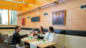 Een restaurant met houten tafels, comfortabele zithoeken en kunst aan de muren.