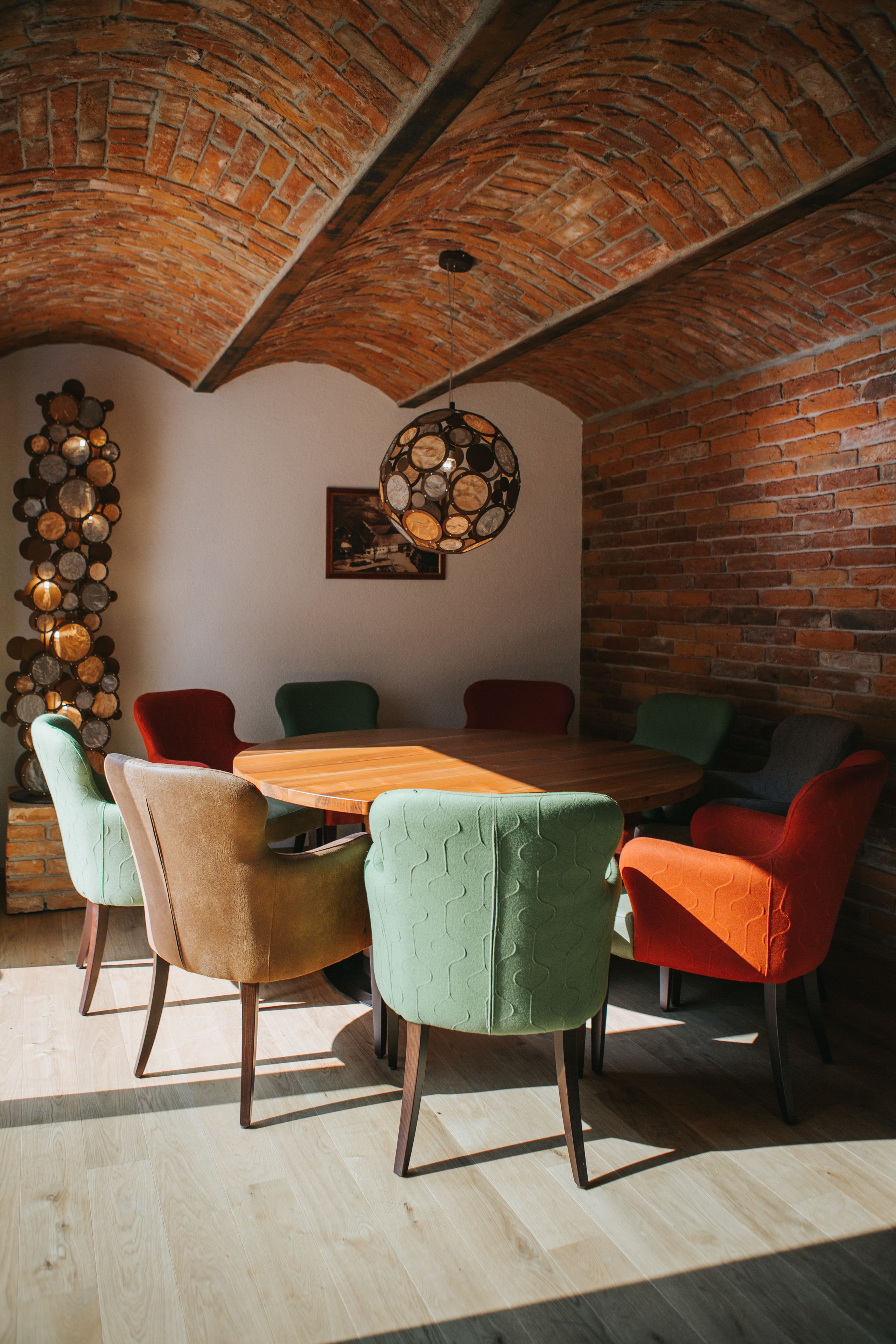 Un coin repas avec un mur en briques, une table en bois et des chaises colorées.