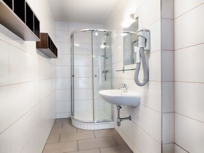 A modern bathroom with a glass shower enclosure, a white sink, and a handheld showerhead. - B&B Hotel Graz-Hbf (Graz)