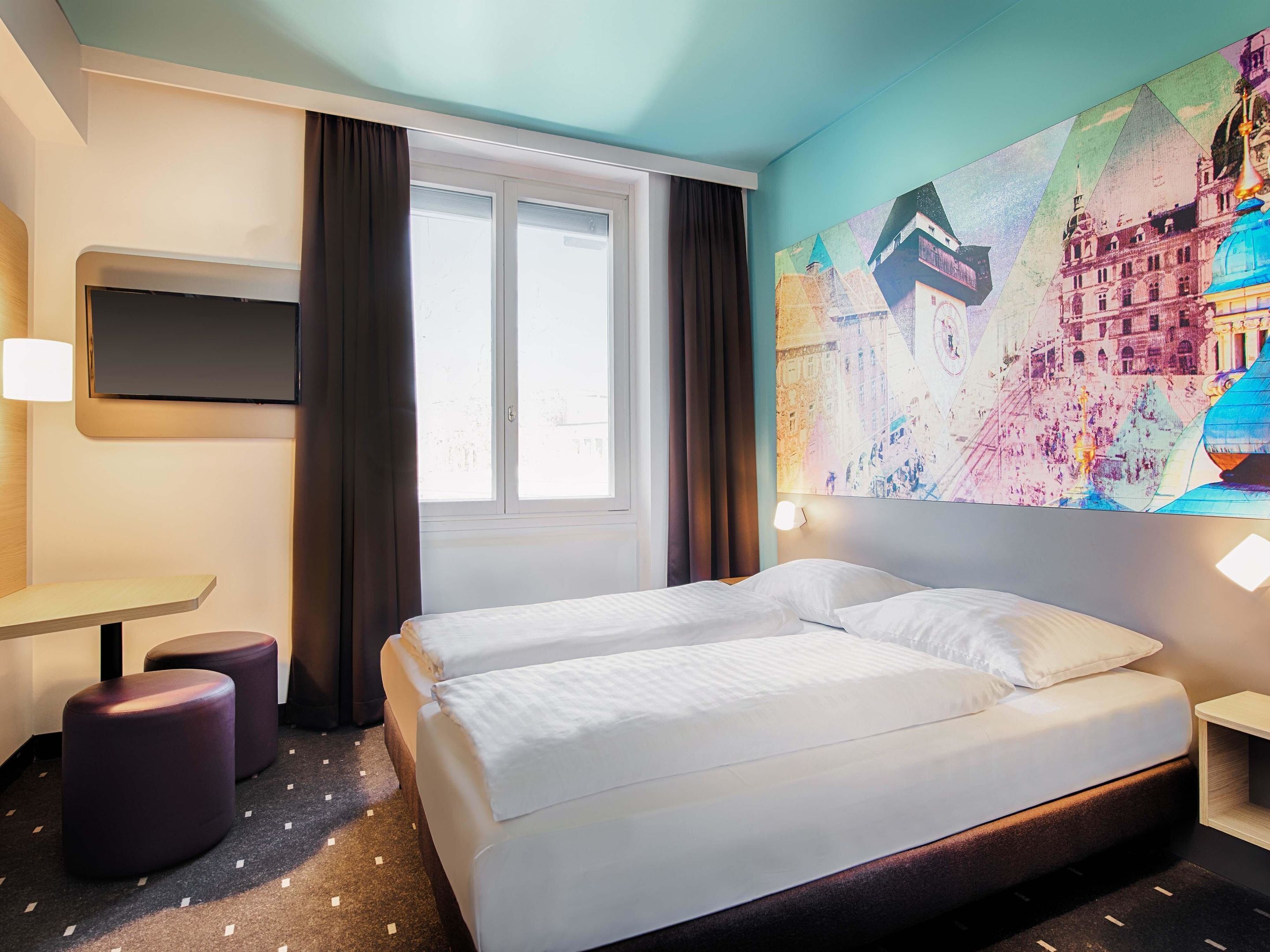 Una camera d'albergo con un letto, una scrivania e un'ampia finestra.