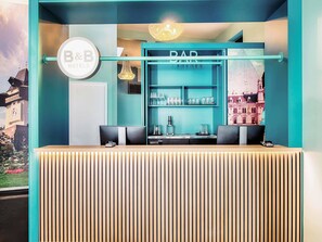 A bar area with a teal color scheme, a B&B Hotels sign, and a counter with glasses and a coffee machine. - B&B Hotel Graz-Hbf (Graz)