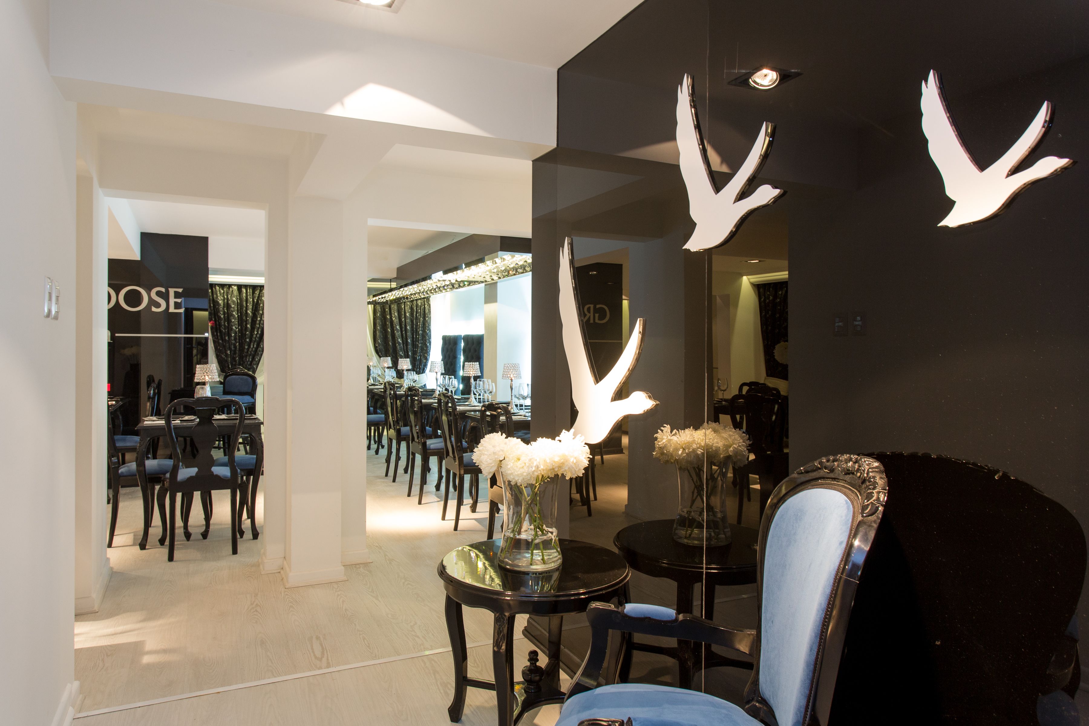 A modern interior with a dining area featuring dark wooden chairs and a round table with a vase of white flowers.