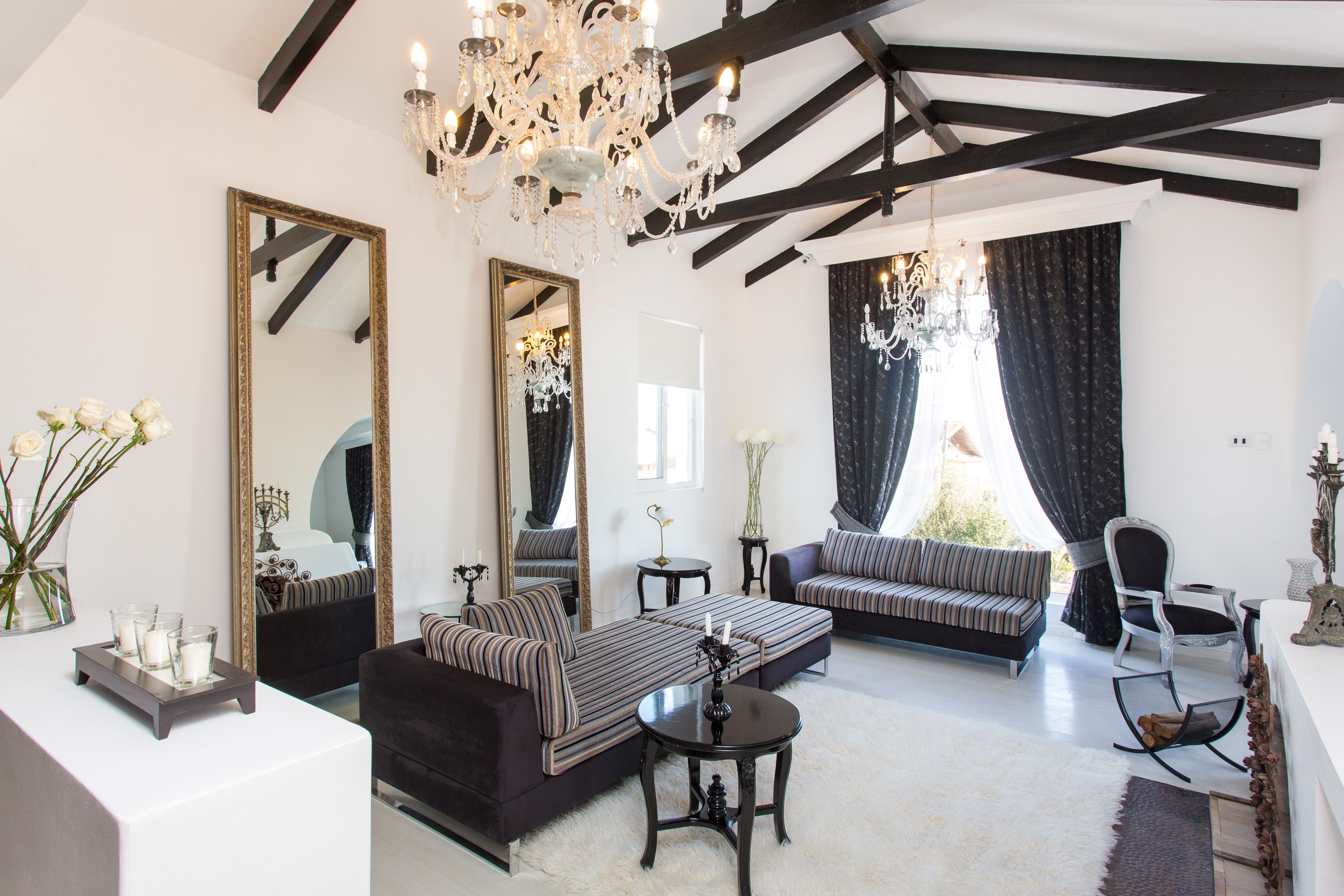 A spacious living room with a large mirror, a chandelier, and a sofa set.