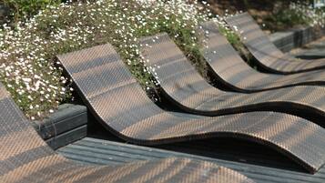 Een rij comfortabele stoelen met een structuurweefsel, gerangschikt achter een tuin.