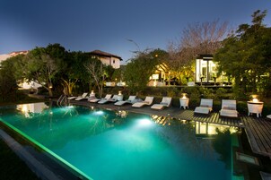 Una piscina con sillas de descanso y un pequeño edificio con luces.