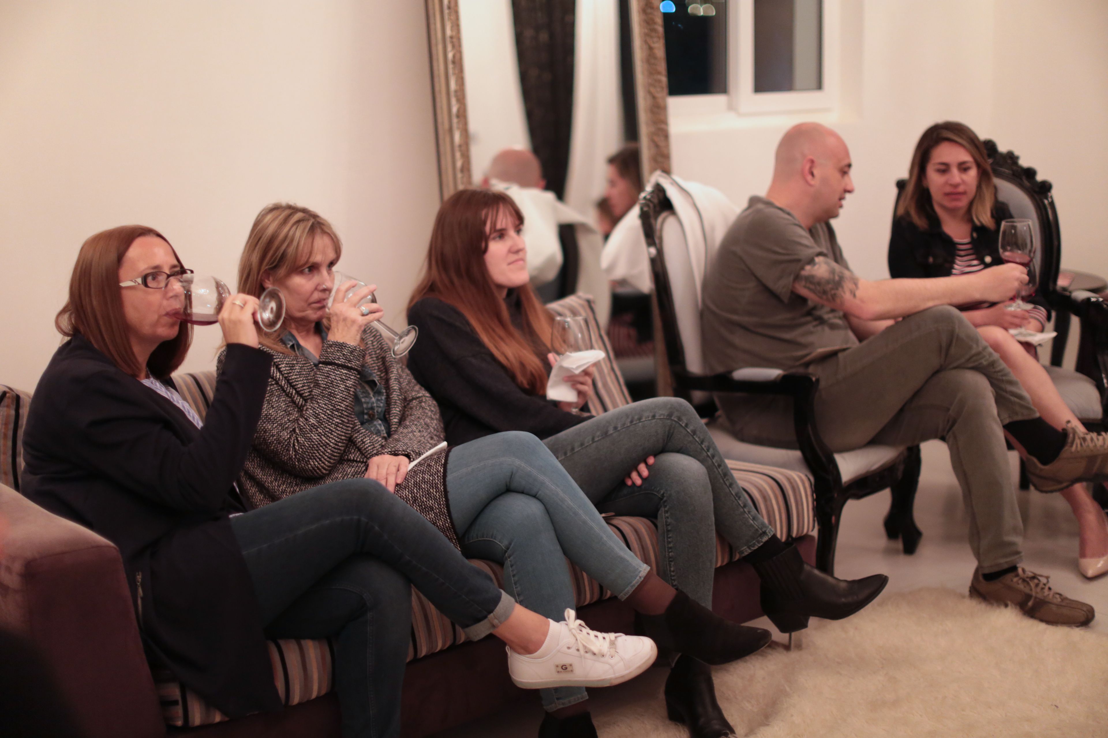 Un grupo de personas sentadas en un sofá en una habitación con un espejo grande y una ventana.