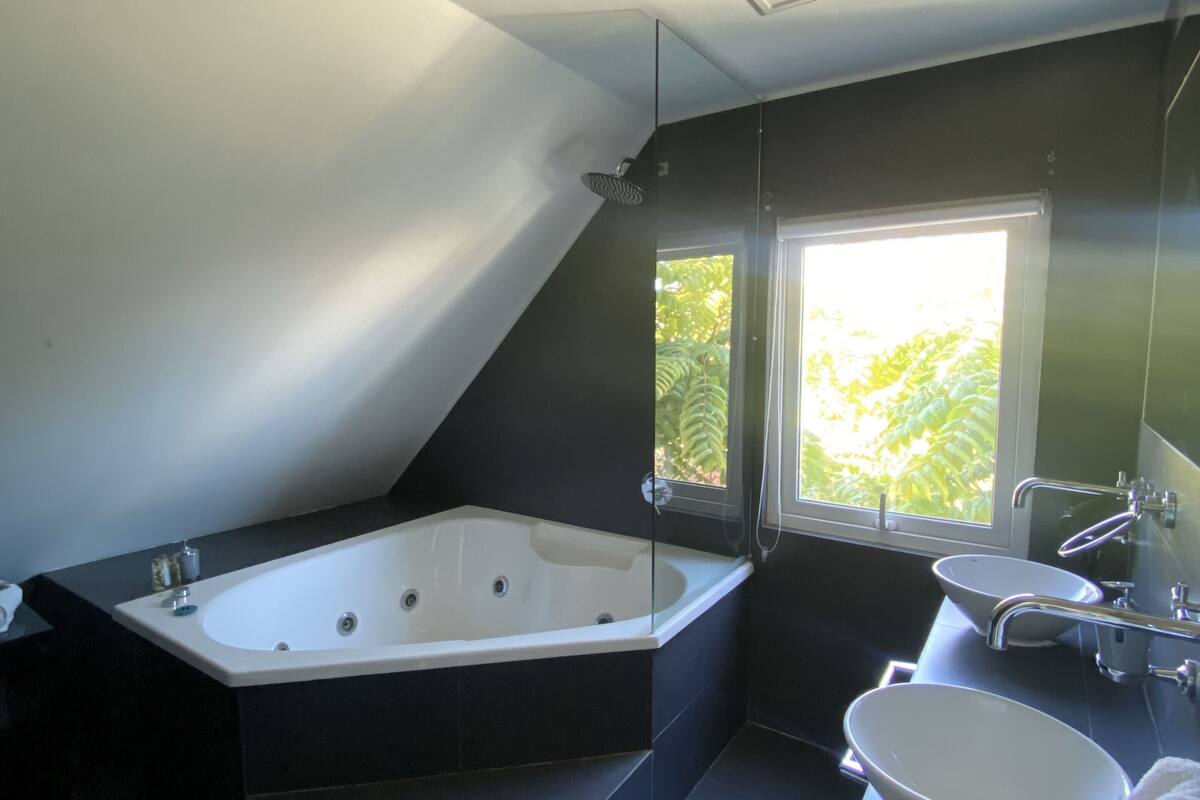 A modern bathroom with a freestanding bathtub, a large window, and a separate sink area.