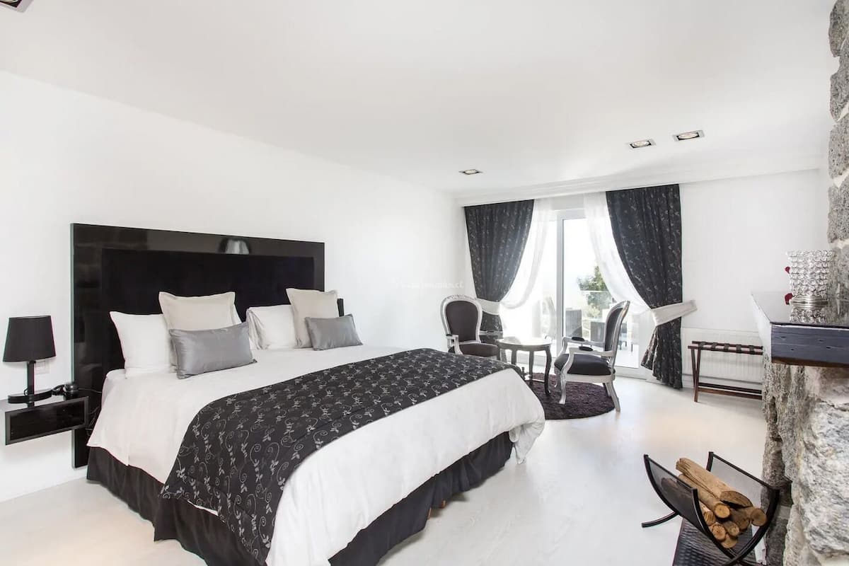 A modern hotel room with a large bed, a seating area, and a stone accent wall.