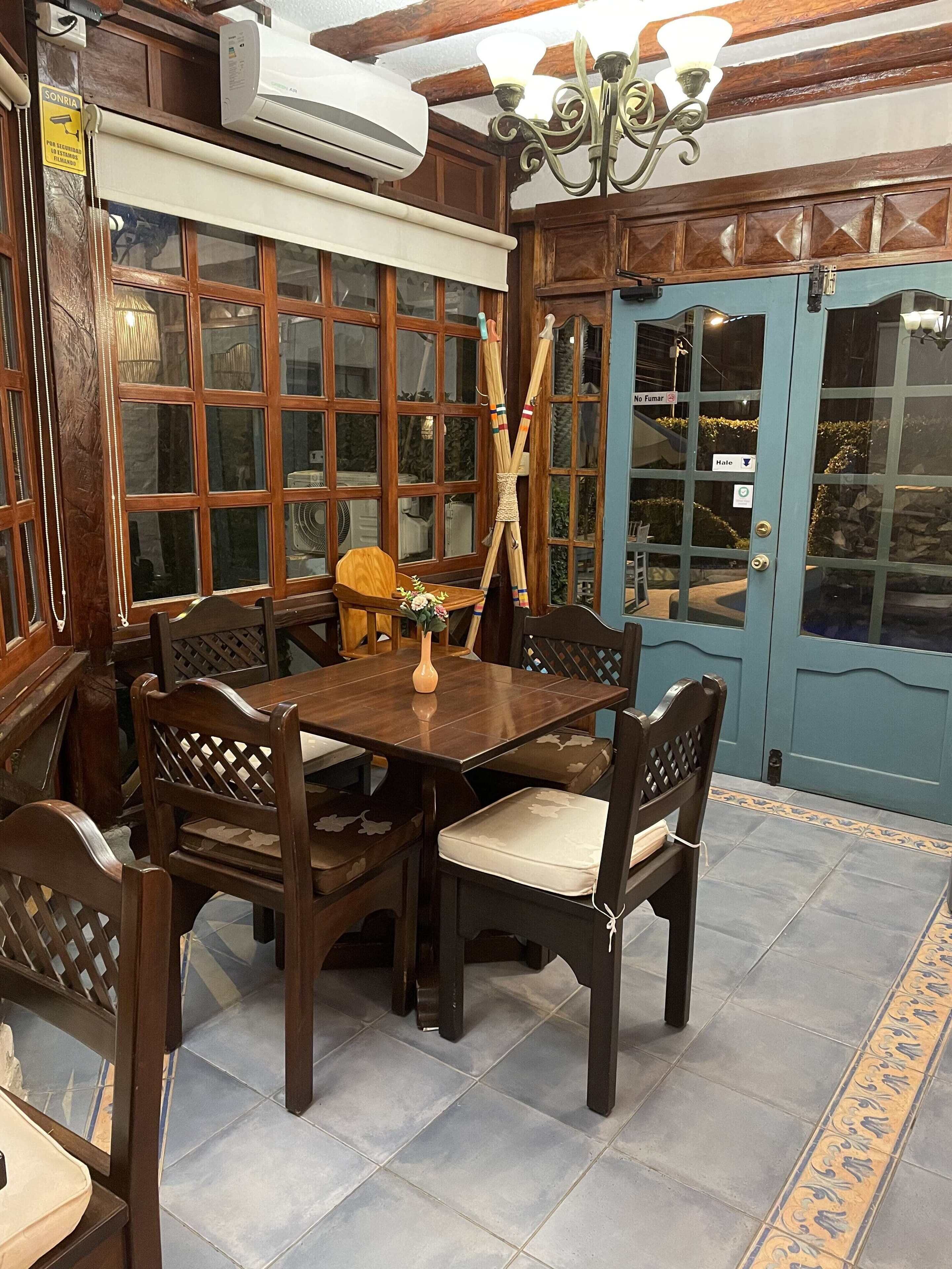 A dining area with a wooden table and chairs, a vase with flowers, and a blue door with a sign.