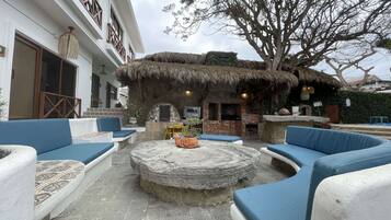 An outdoor seating area with blue cushioned sofas and a stone fire pit.