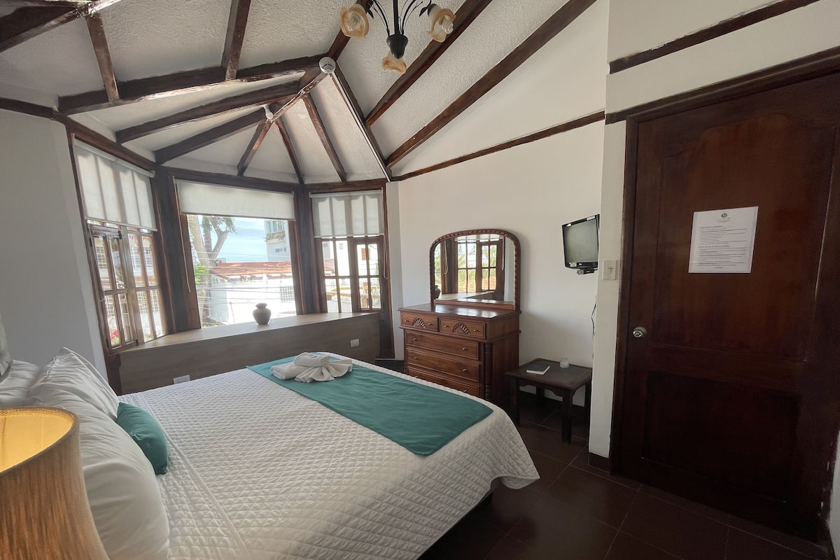A bedroom with a bed, dresser, mirror, and a television.