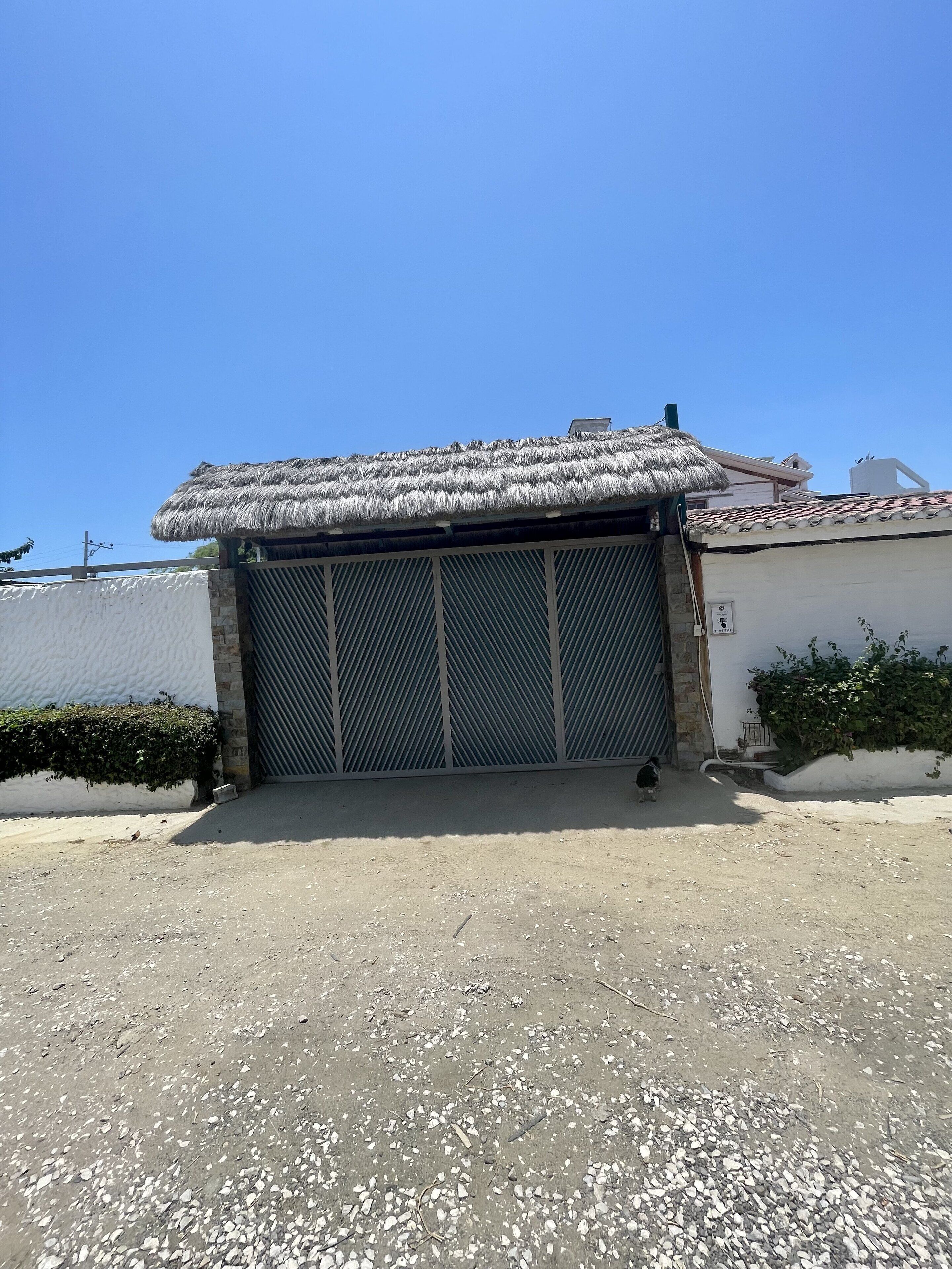 A building with a thatched roof, a metal gate, and a gravel driveway.