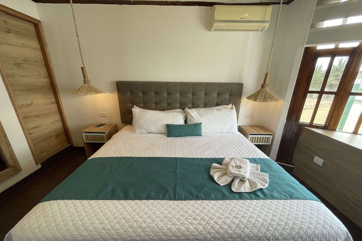 A neatly made bed with a quilted bedspread, pillows, and a folded towel on the bed.
