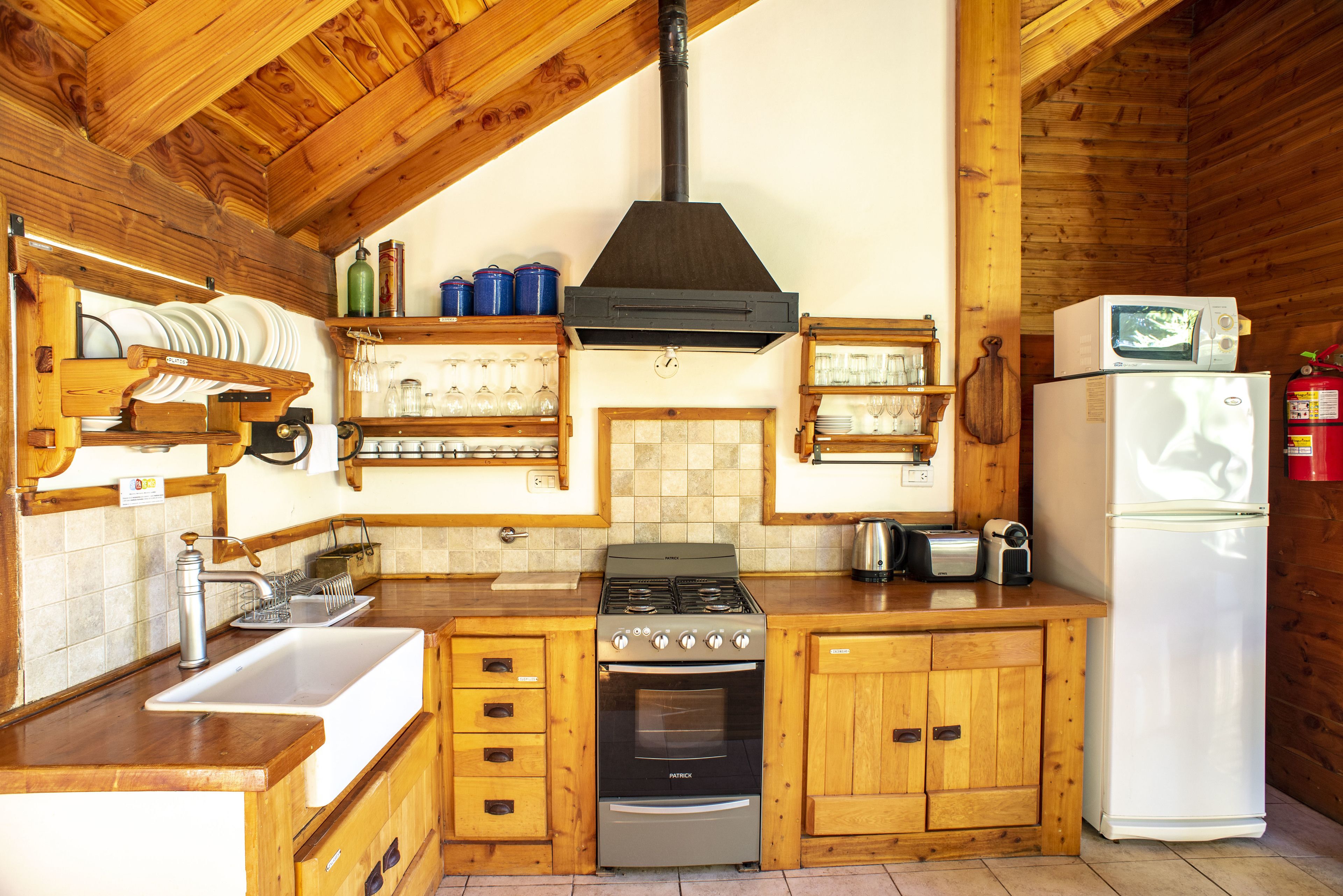Una cocina de madera con estufa, lavaplatos y microondas.