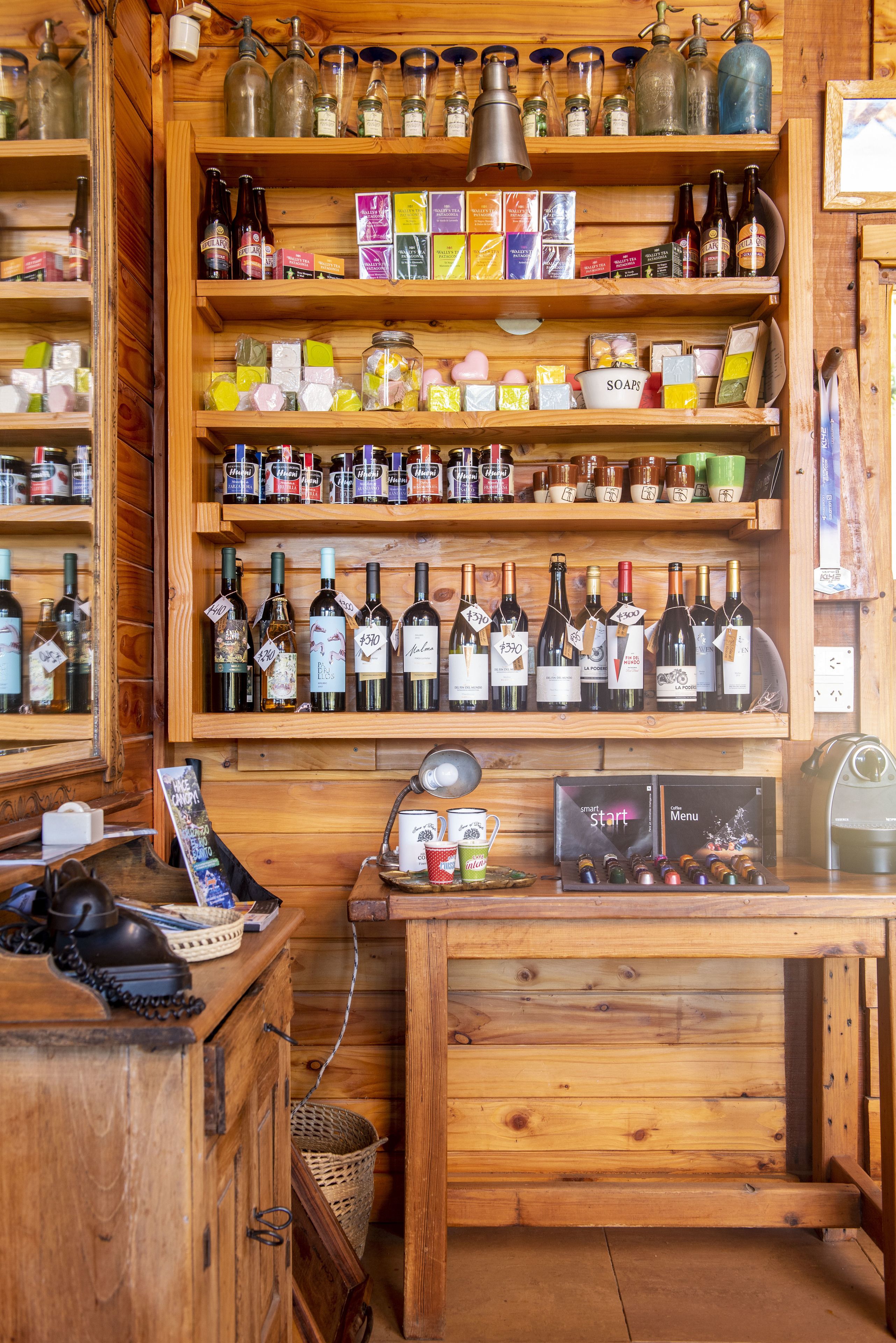 Un interior de madera con estantes que exhiben varias botellas y cajas, un escritorio con un teléfono y un atril para menús.